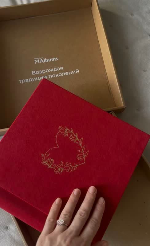 Красный велюровый альбом с золотым тиснением сердца в венке, его достают из фирменной коробки